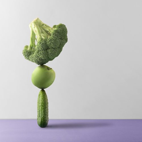 Concept of nutritional balance. Fresh fruits and vegetables are balanced against a gray background.